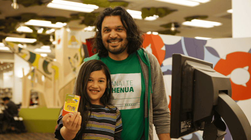 Man with girl showing library card