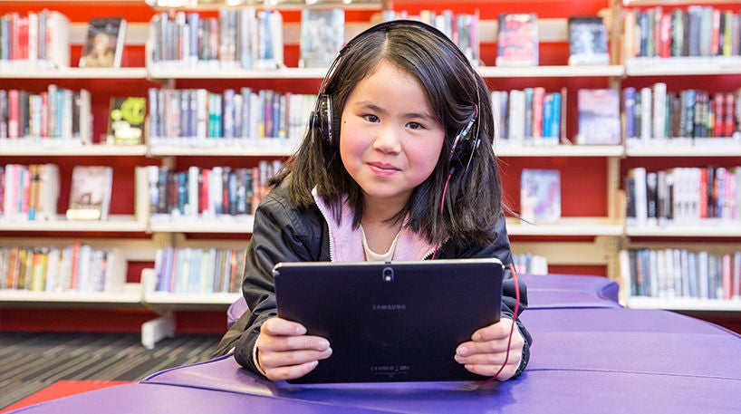 A child using an iPad in the library