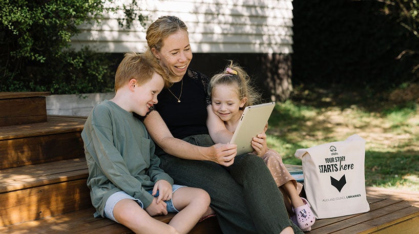 Mother and two children using a tablet outdoors