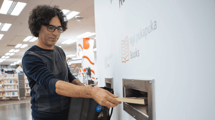Man returning a book at the returns chute