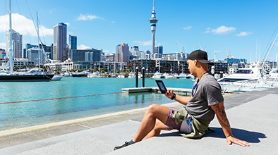 Young man using an ereader while out in Auckland city